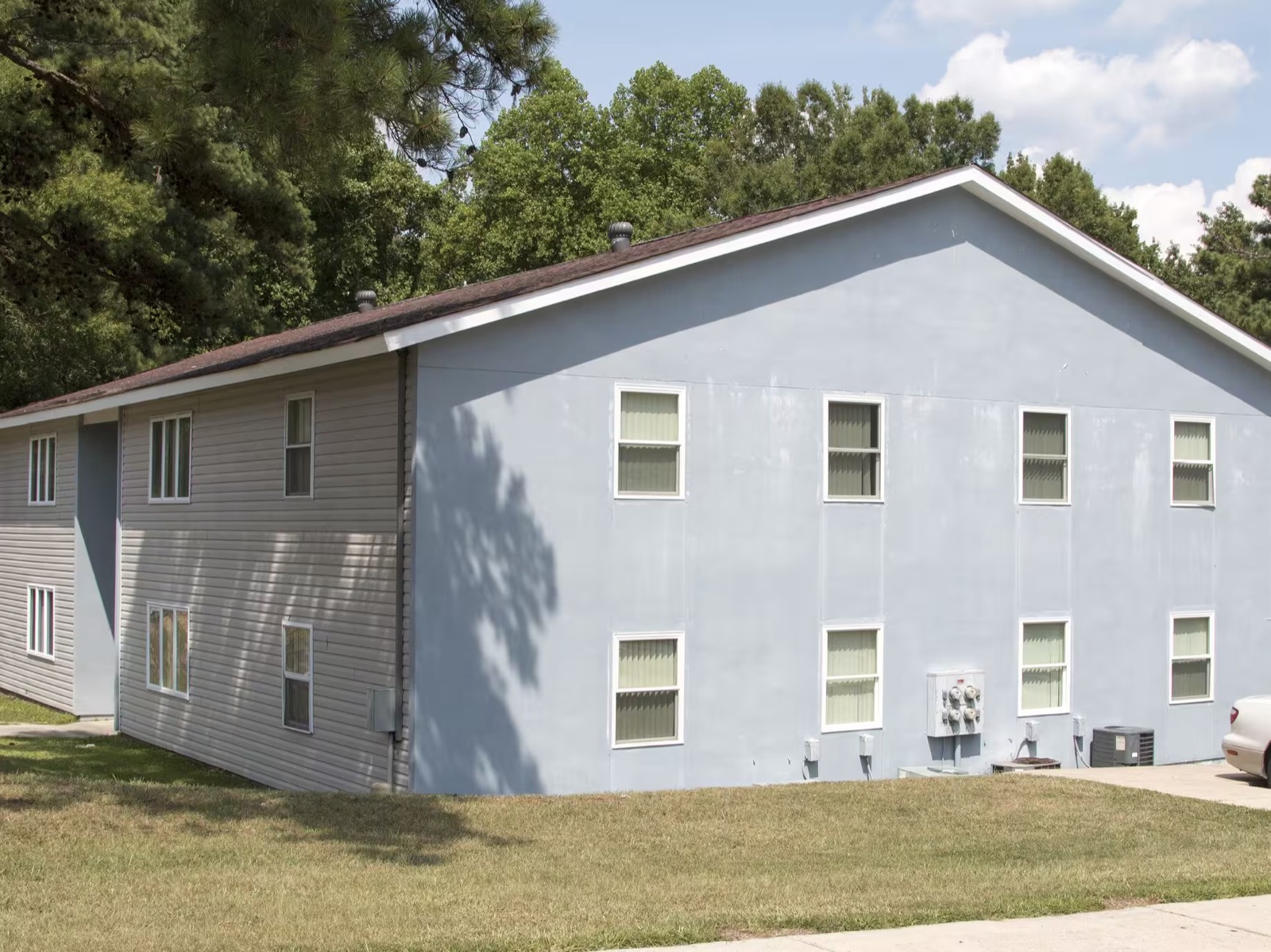 Blue-gray gable end of an apartment building at Mauldin Village beside a wide community lawn