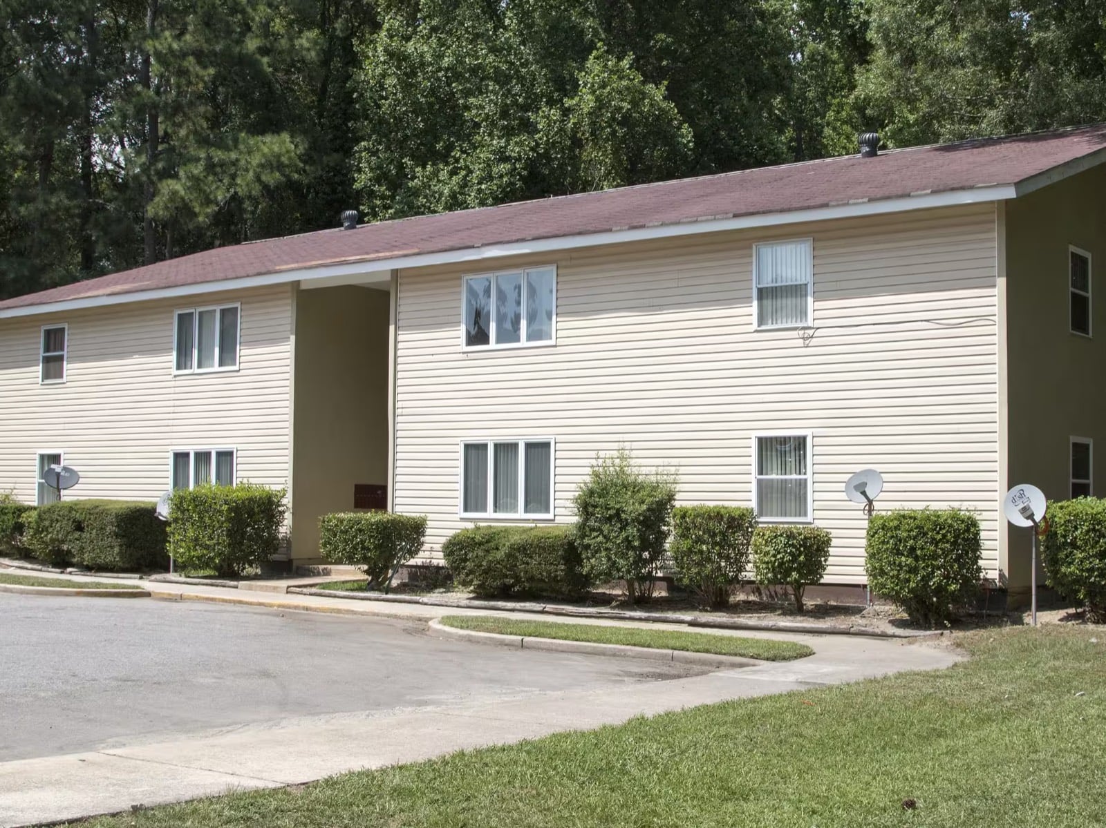 Front of a two-story apartment building at Mauldin Village with landscaped shrubs and a breezeway entrance