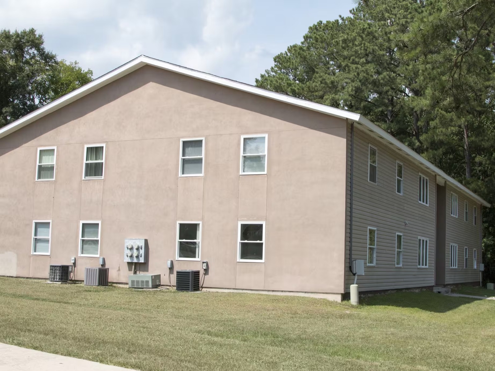 Side of a two-story apartment building at Mauldin Village with open lawn and wooded surroundings